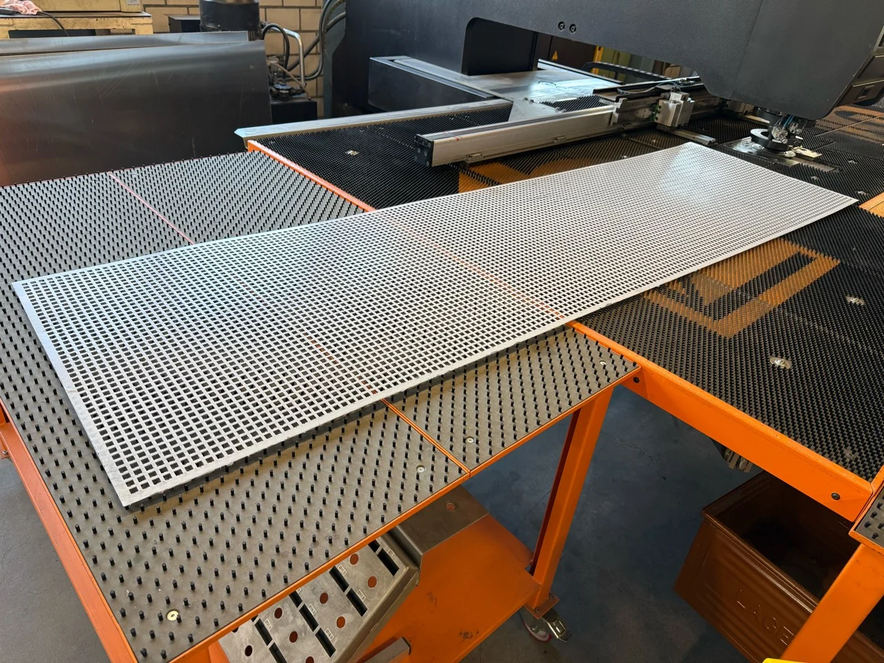 Langes Aluminium-Lochblech mit Quadratlochung Qg 10/15 auf der Stanzmaschine bei 2B Metall AG